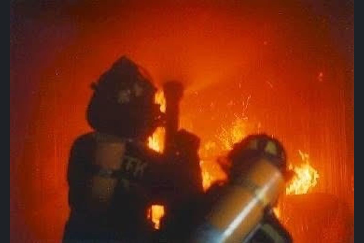 A firefighter advancing a hoseline into heavy fire during an interior attack
